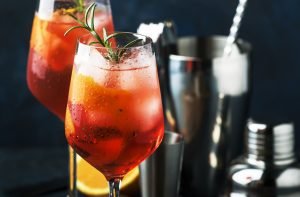 Duas taças de Aperol Spritz bem geladas com ramo de alecrim, apresentando gotas de água condensada no vidro da taça.