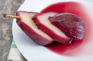 Pera cozida ao vinho do Porto servida em prato branco