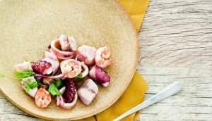 Ceviche de frutos do mar servido em prato rústico