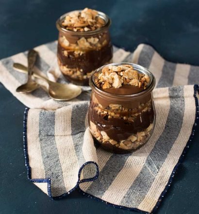 Sobremesa de surpresa de chocolate belga com creme de avelã e crocantes em copos com granulado, acompanhada de pote de chocolate