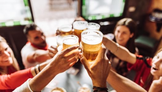 Grupo de pessoas brindando com cerveja em um bar