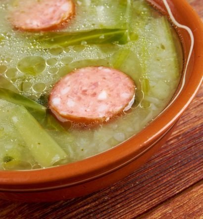 Caldo verde com rodelas de linguiça portuguesa servido em tigela de barro