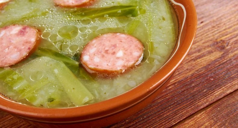 Caldo verde com rodelas de linguiça portuguesa servido em tigela de barro