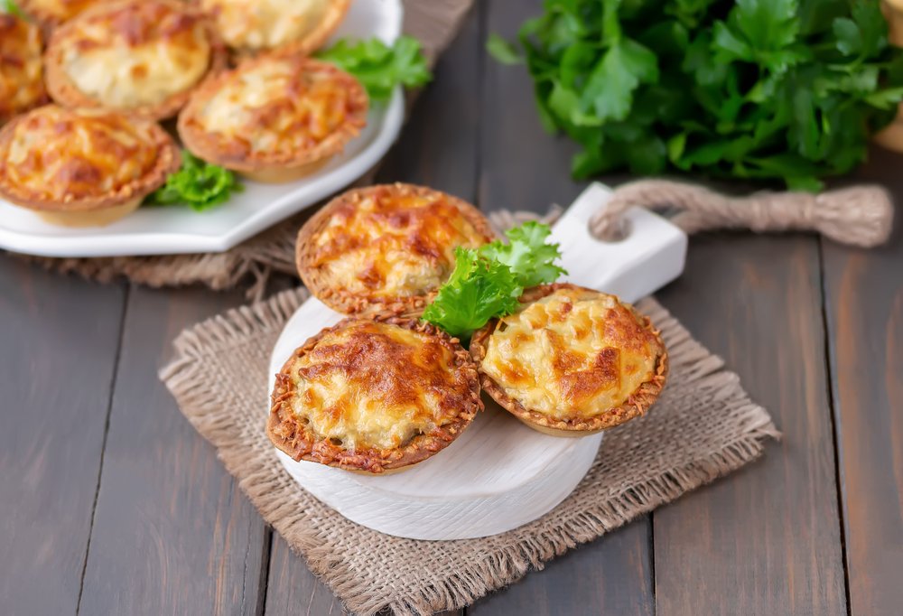 Empadinhas assadas com recheio de carne e queijo, guarnecidas com salsa fresca, ideais para piquenique