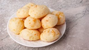 Pão de queijo caseiro servido em um prato branco com textura dourada