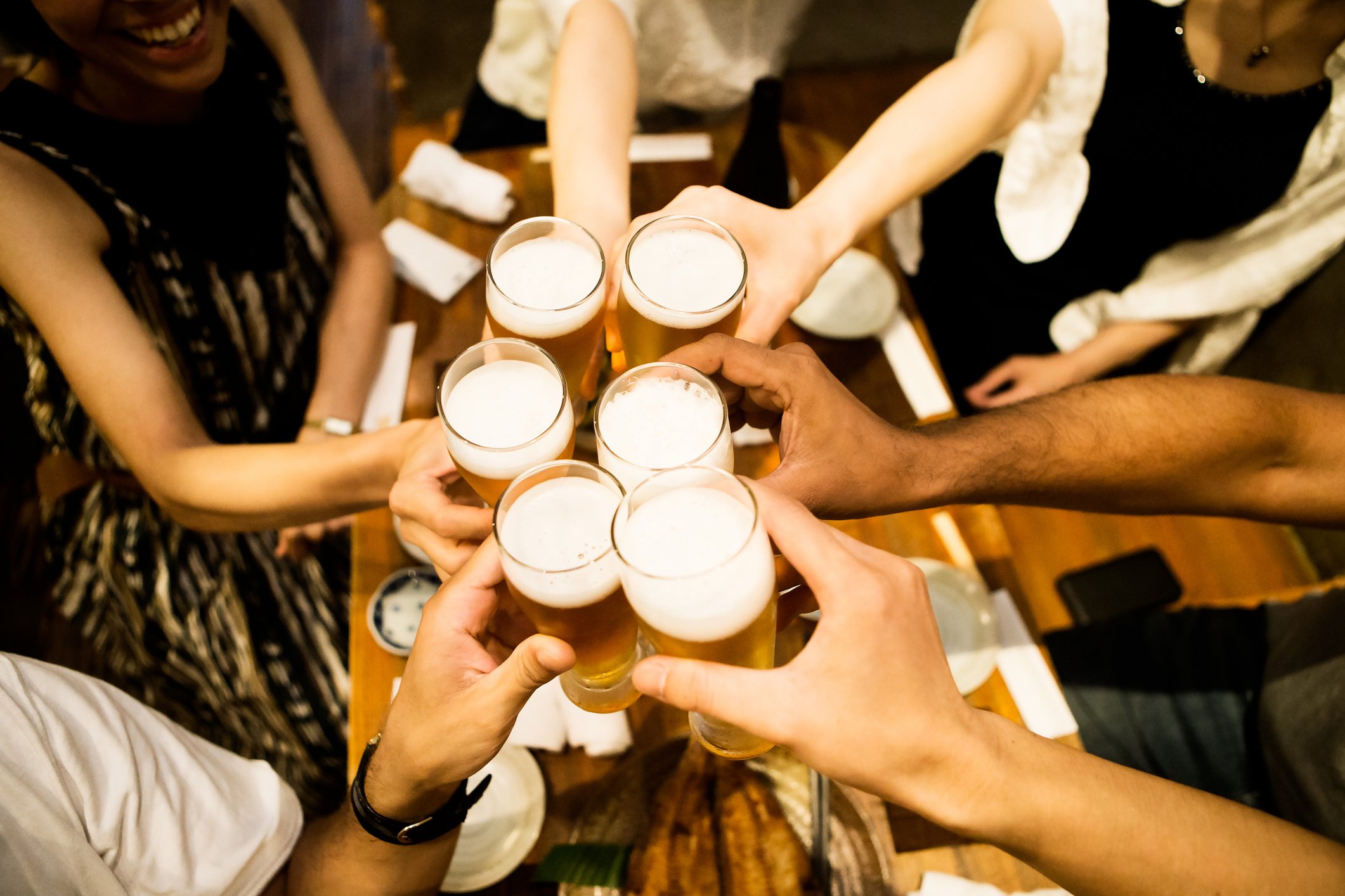 grupo de pessoas levantando copos de cerveja em celebração.
