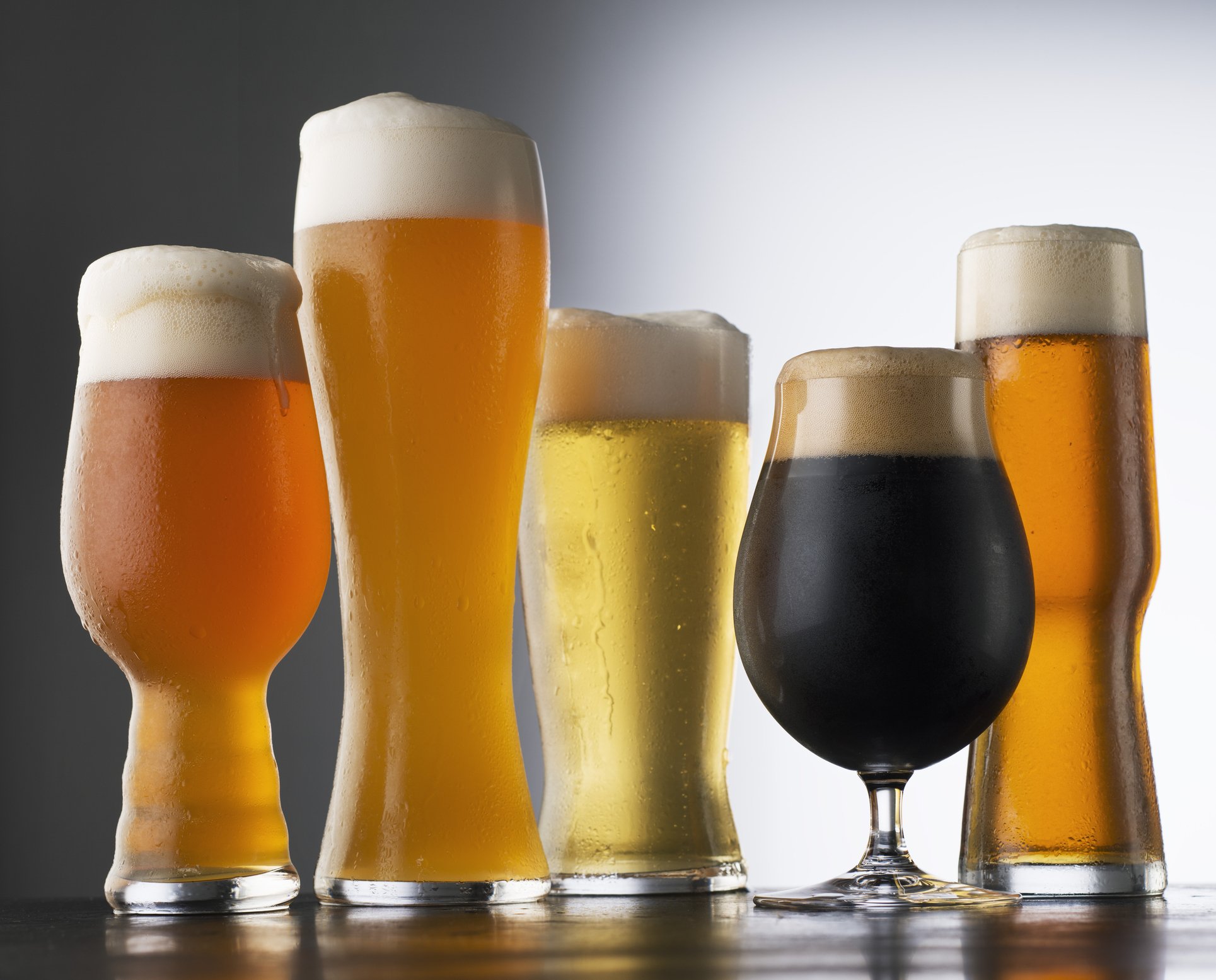 diferentes copos de cerveja com espuma.