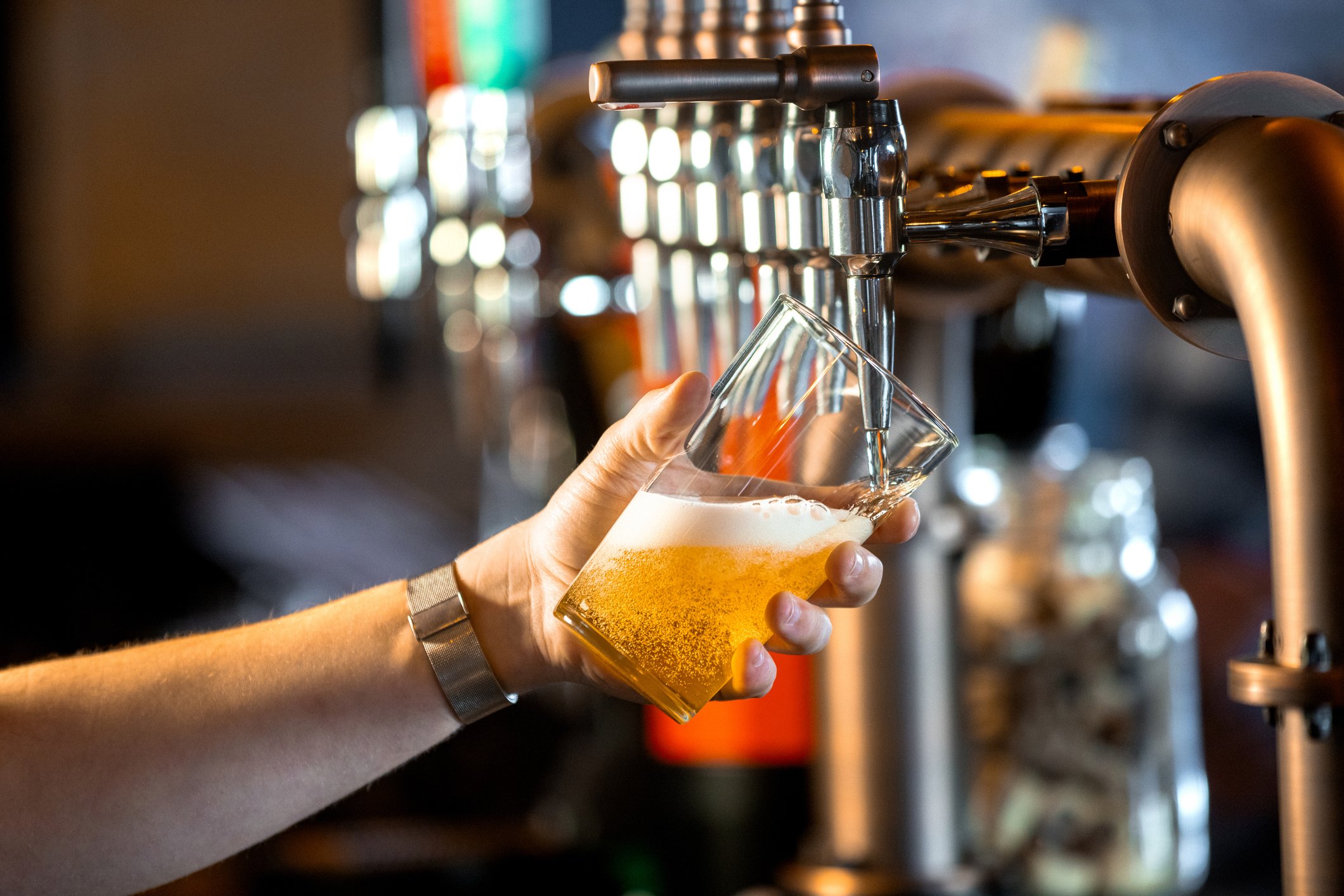 mão servindo cerveja em um copo.