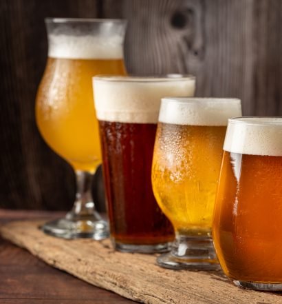 quatro copos de cerveja diferentes em uma mesa de madeira.