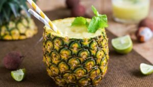 Drink refrescante servido dentro de um abacaxi com folhas de hortelã