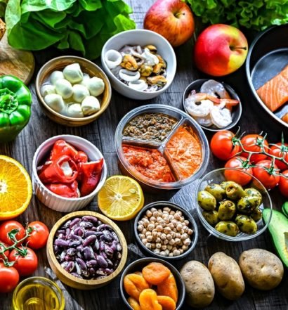 Variedade de alimentos frescos da pirâmide alimentar — vegetais, frutas, proteínas e grãos organizados sobre superfície escura, representando uma alimentação equilibrada.