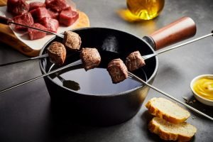 Ingredientes para fondue de carne sobre uma mesa.