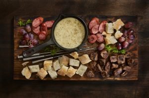 Fondue de queijos frescos com acompanhamentos variados.