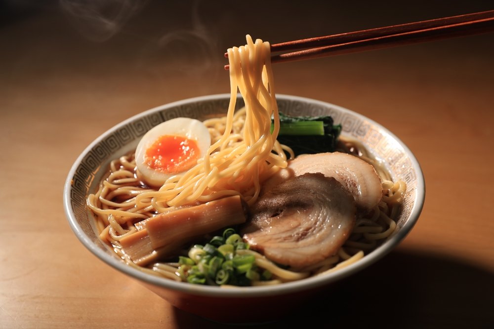 lamen com ovo ajitama, chashu e noodles sendo levantados por hashis