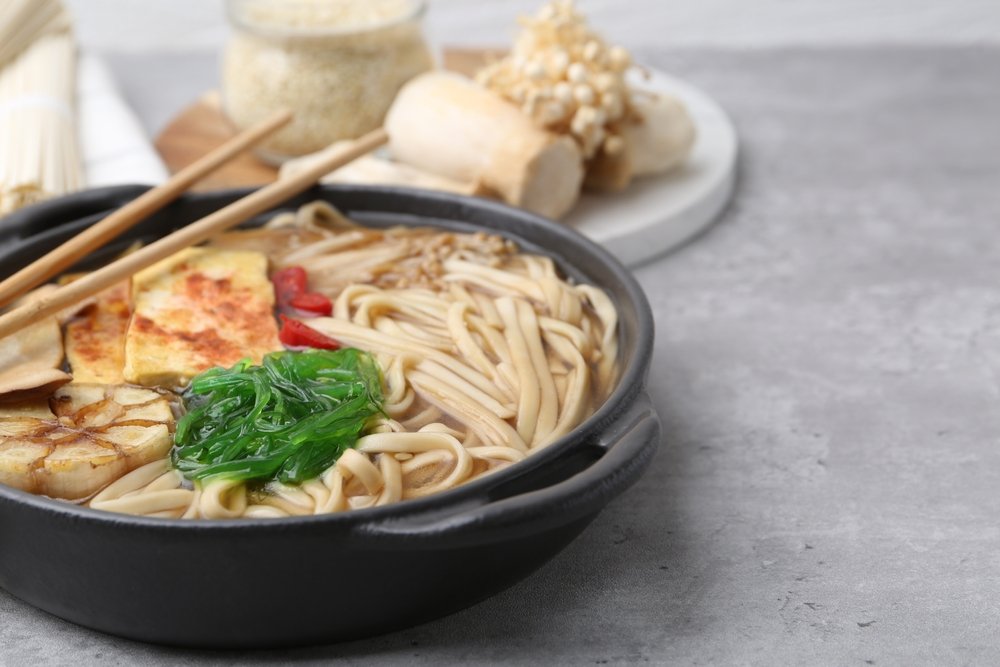 lamen vegetariano com cogumelos enoki, tofu e algas em caldo claro