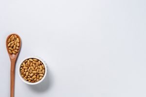 Feijão-jalo cru em colher de madeira e potinho branco sobre fundo claro, tipo de feijão entre os 11 grãos mais consumidos