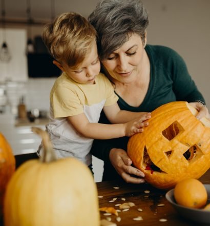 Adulto e criança decorando abóbora Jack-o'-lantern na cozinha para festa de Halloween