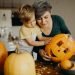 Adulto e criança decorando abóbora Jack-o'-lantern na cozinha para festa de Halloween