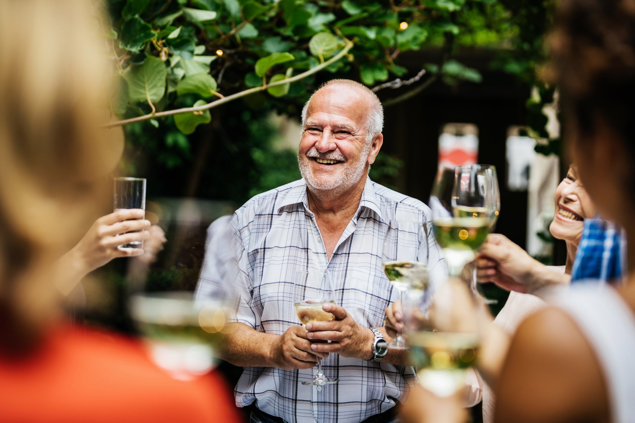 Homem brindando com taças de vinho ao redor de muita gente segurando taça