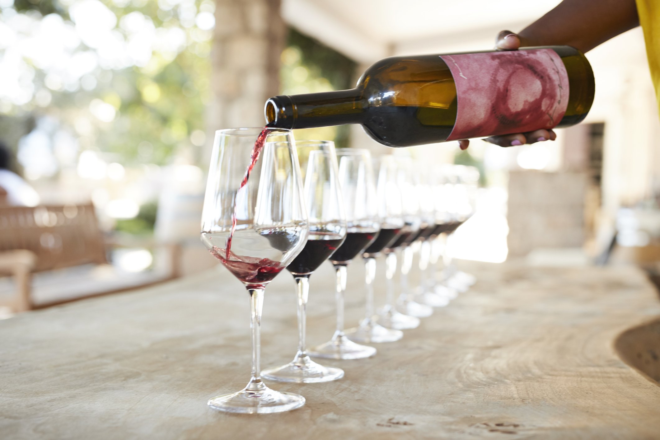 Vinho tinto sendo servido em fila de taças; consumo moderado associado a menor risco de diabetes tipo 2.