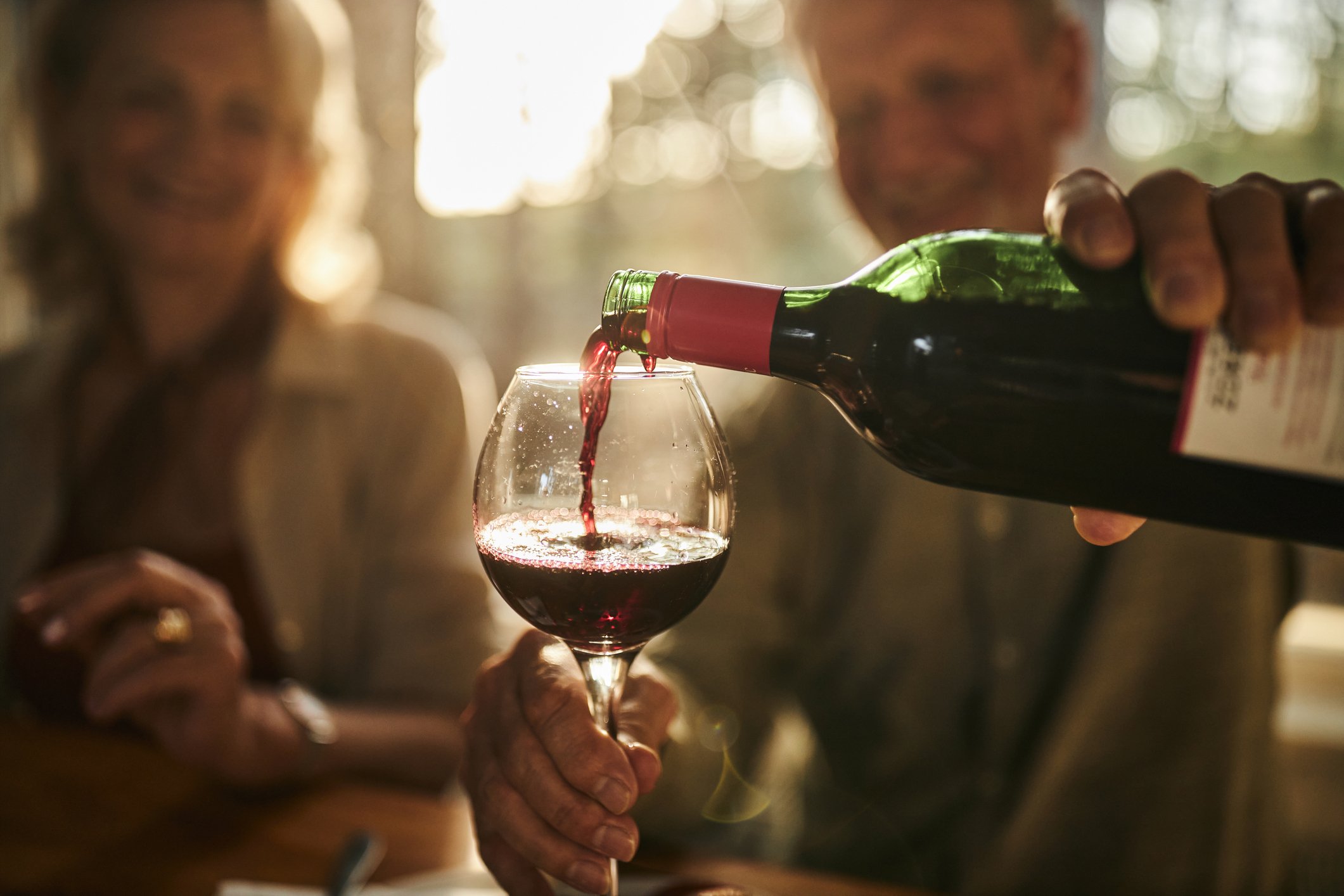 Vinho tinto sendo servido em taça durante uma refeição