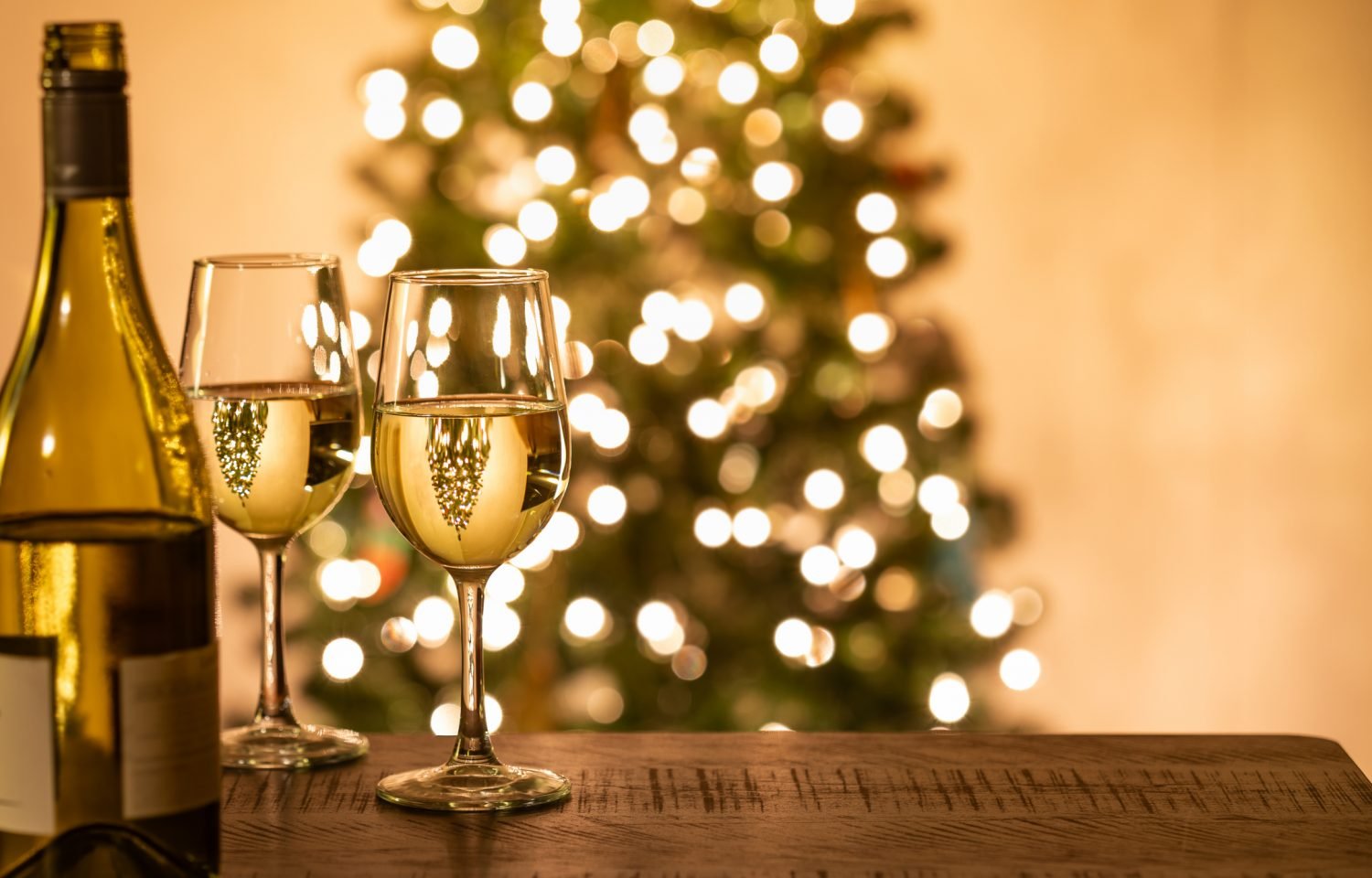 Taças de vinho com luzes de árvore de Natal ao fundo, sugestão de vinhos para a ceia de Natal para impressionar convidados