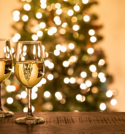 Taças de vinho com luzes de árvore de Natal ao fundo, sugestão de vinhos para a ceia de Natal para impressionar convidados