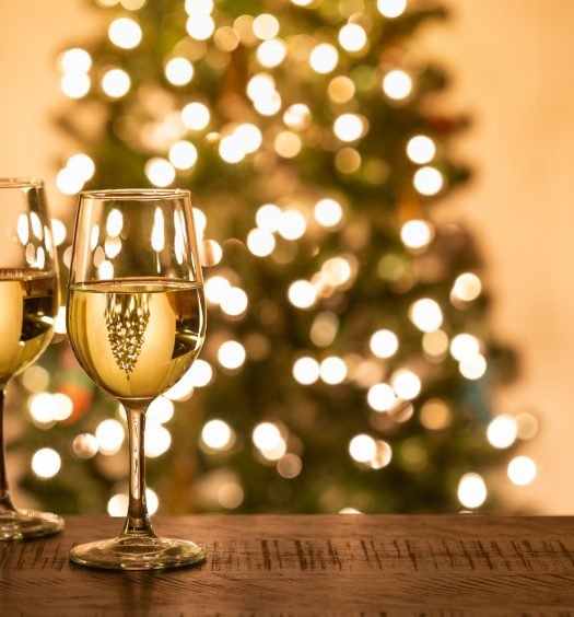 Taças de vinho com luzes de árvore de Natal ao fundo, sugestão de vinhos para a ceia de Natal para impressionar convidados
