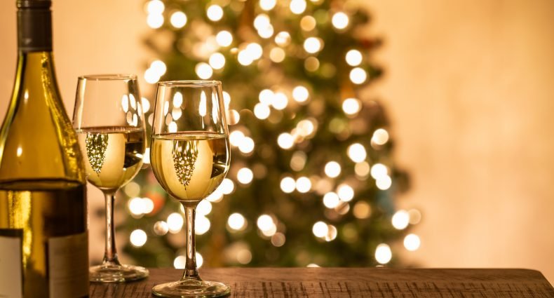 Taças de vinho com luzes de árvore de Natal ao fundo, sugestão de vinhos para a ceia de Natal para impressionar convidados