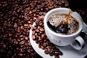 Café sendo servido em uma xícara com grãos ao redor