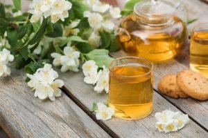Chá verde com flores de jasmim em xícara e bule