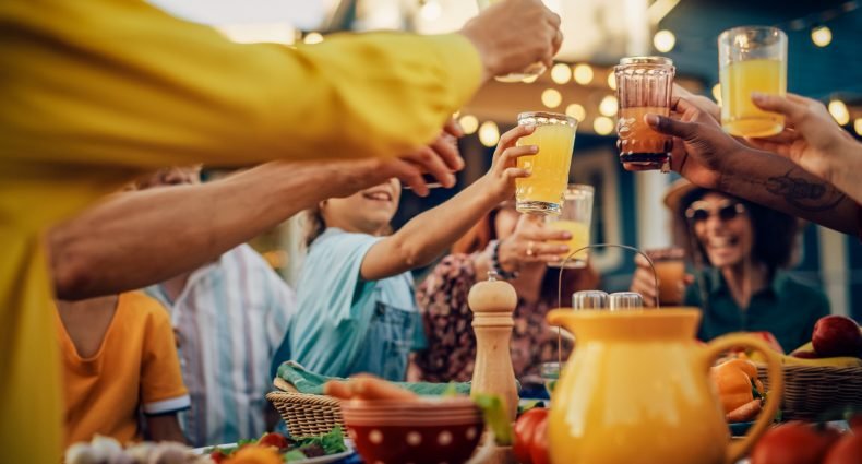 Pessoas ao redor de uma mesa brindando com drinques sem álcool