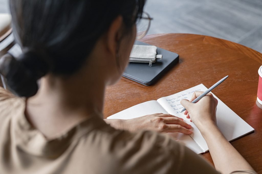 Mulher escrevendo em um caderno em um momento de reflexão