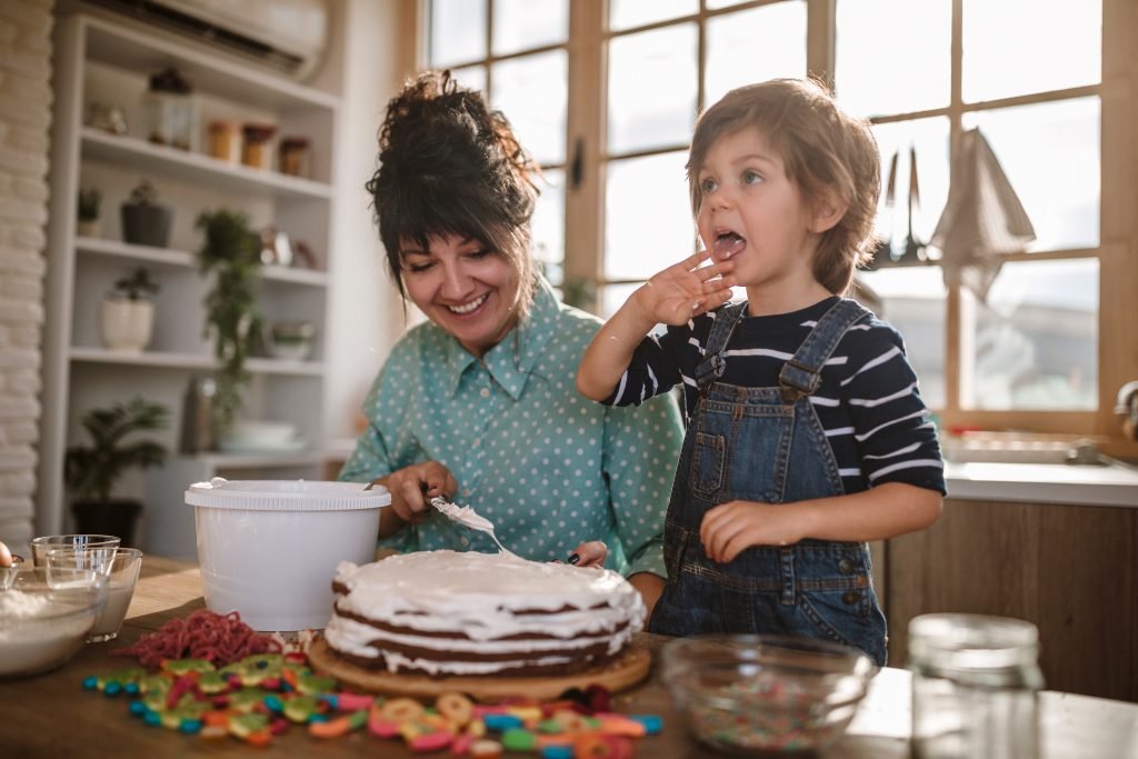 Mãe e filho decorando um bolo juntos