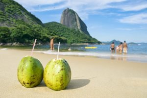 Dois cocos verdes com canudos na areia da praia