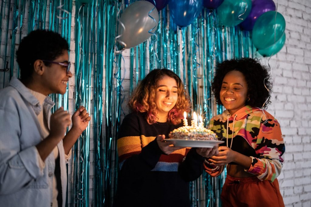 Jovens celebrando aniversário com bolo e decoração colorida