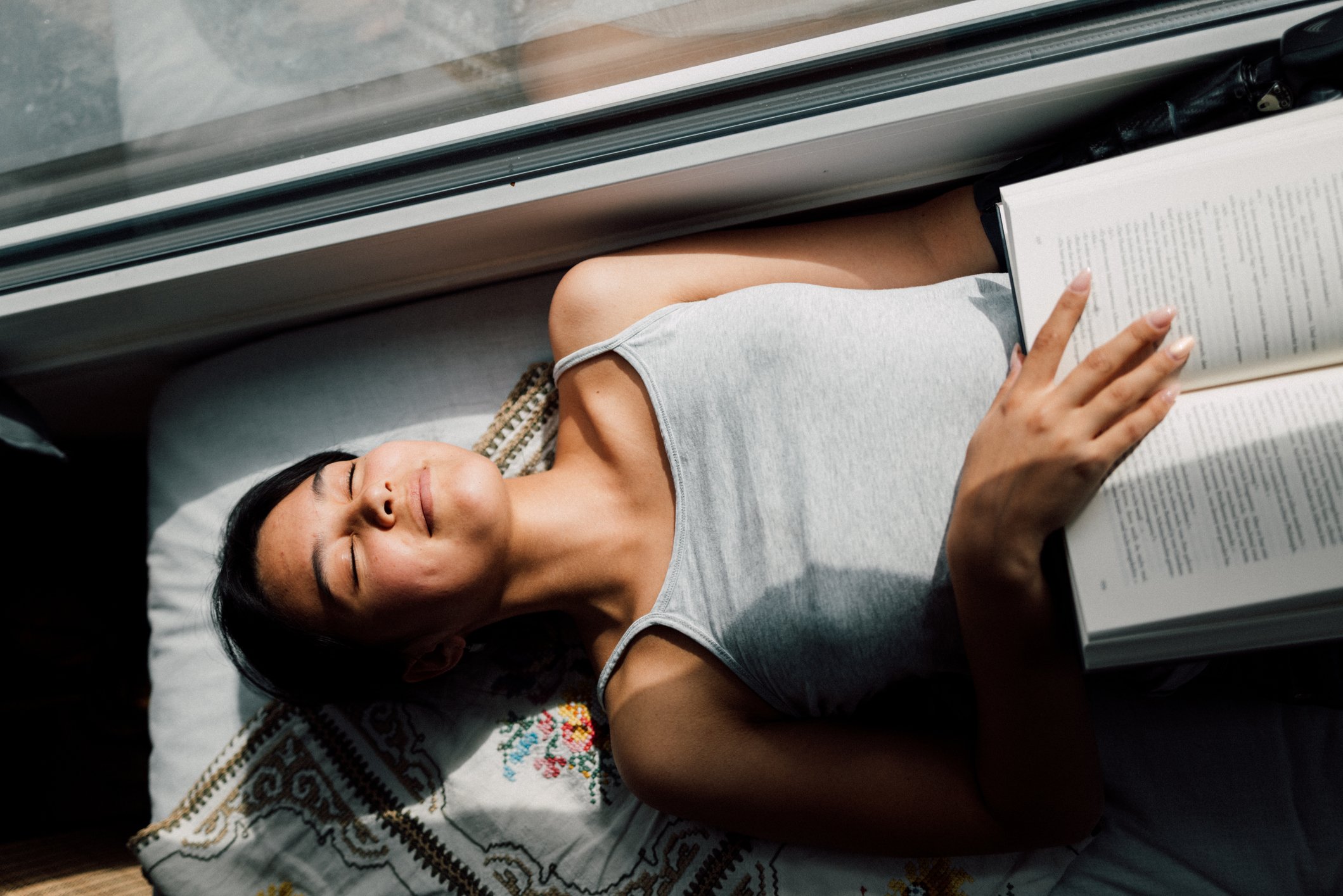 Mulher relaxando e lendo livro em casa, destacando a importância de momentos de lazer para a saúde mental