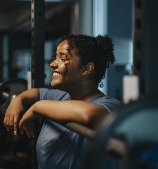 Mulher sorridente relaxando na academia após o treino