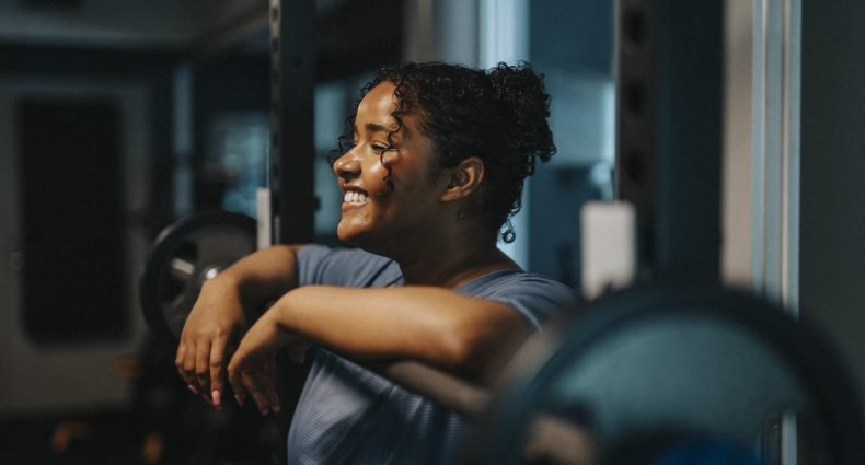 Mulher sorridente relaxando na academia após o treino