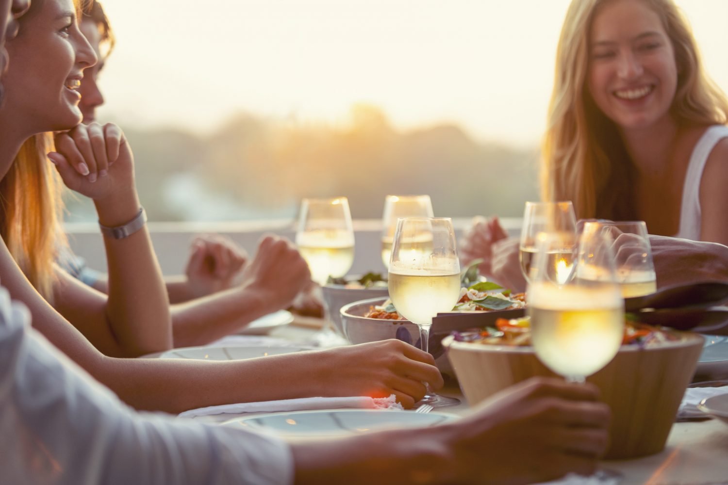 Pessoas felizes compartilhando uma refeição ao ar livre com drinks e pratos leves