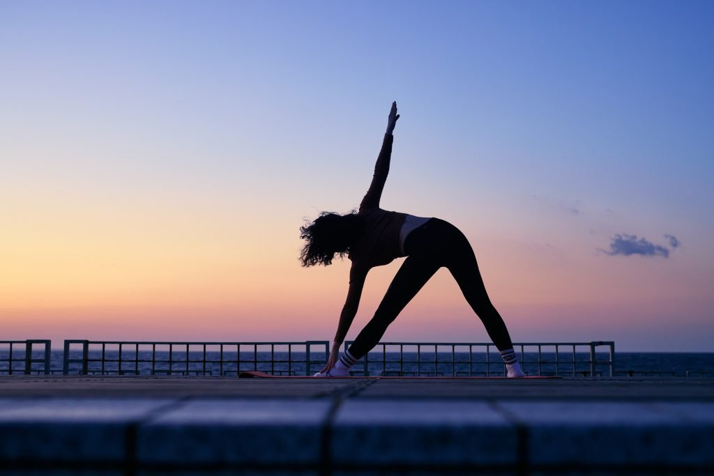 Mulher praticando yoga no nascer do sol