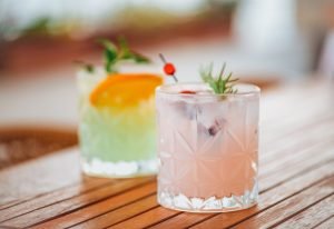Copos de gin tônica coloridos sobre uma mesa de madeira