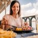 Mulher sorrindo enquanto come uma refeição em um restaurante à beira-mar