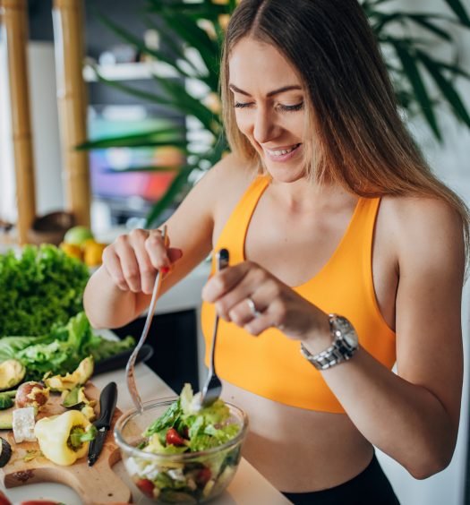 Mulher sorridente preparando uma salada em uma cozinha moderna