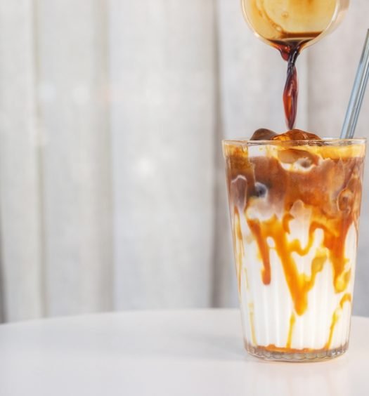Preparação de café gelado com caramelo em um copo transparente
