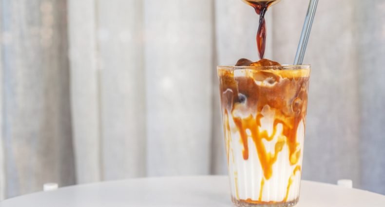 Preparação de café gelado com caramelo em um copo transparente
