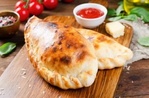 Dois calzones de batata com molho ao fundo