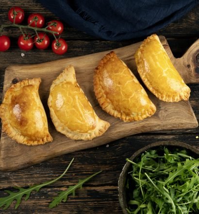 Quatro calzones assados em uma tábua de madeira
