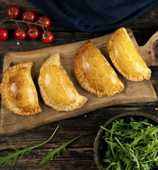 Quatro calzones assados em uma tábua de madeira