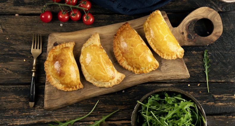Quatro calzones assados em uma tábua de madeira